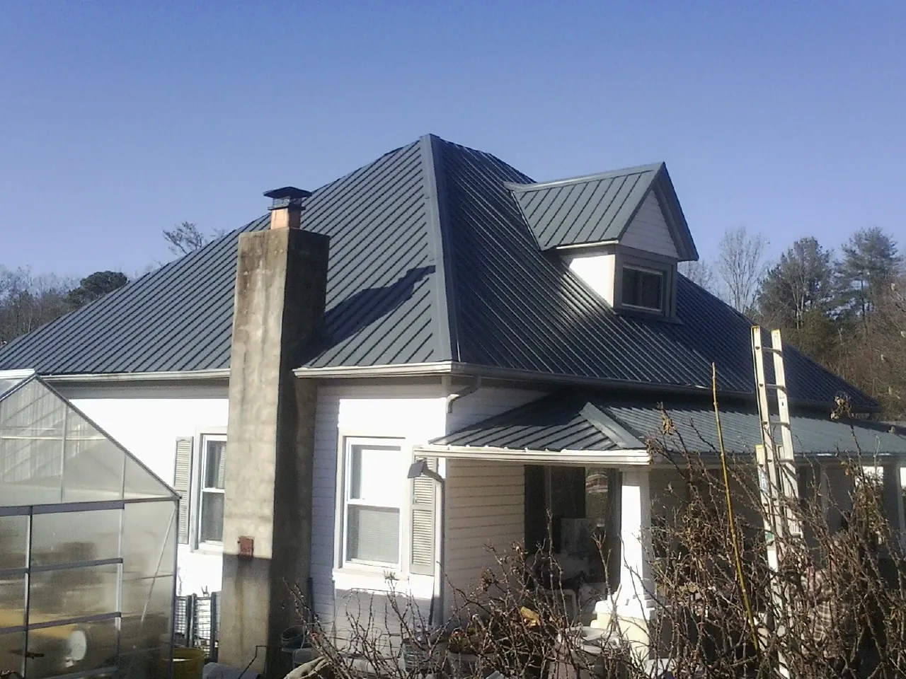 Dark blue standing seam metal roof on a white farmhouse with dormer — Slate & Tile Roof Repair by Roofing Brothers in Montgomeryville