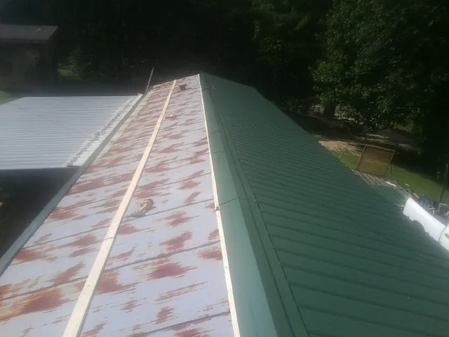 Old rusted panels beside newly installed green metal roofing — Wind Damage Roof Repair by Roofing Brothers in Montgomeryville