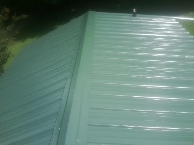 New green metal panels meeting at the ridge of a roof — Flat Roof Repair work by our crew in Montgomeryville