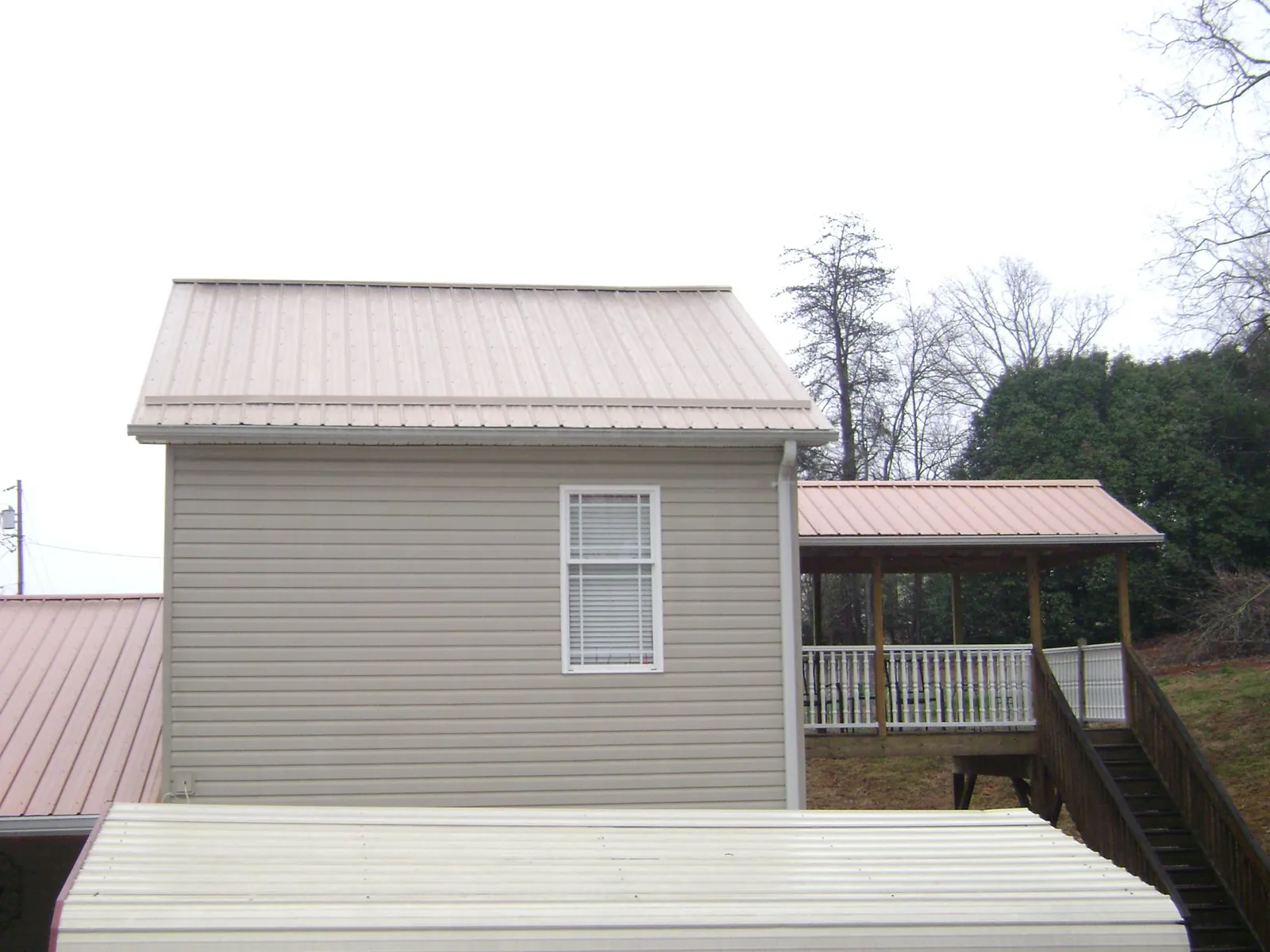 Tan metal roofs on a two story addition and attached porch, from a Roof Replacement job in Montgomeryville