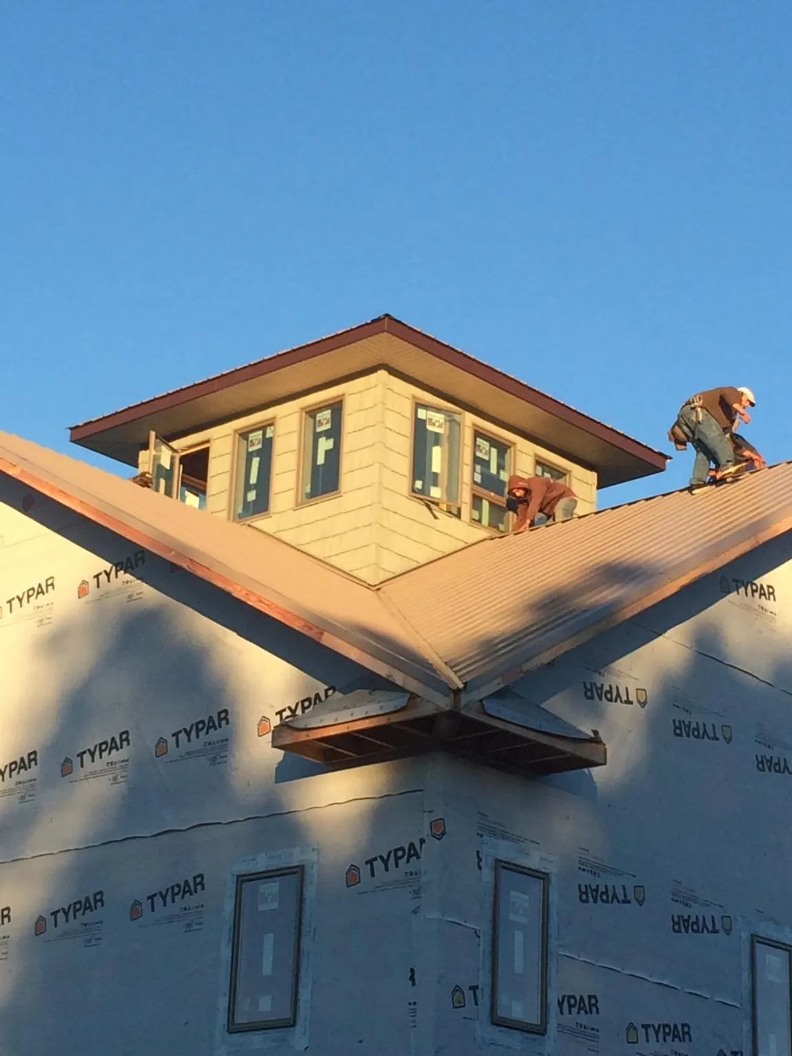 Roofers working around a rooftop cupola on a new metal roof at sunset — Roof Waterproofing in Montgomeryville by Roofing Brothers